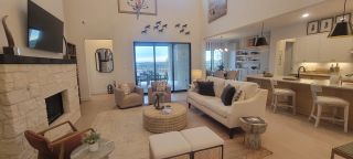 Model Home An inviting living area with a cozy fireplace, plush seating, and open layout leading to a stylish kitchen and dining area.