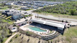 Aerial view of a community center and pool in Whisper Valley by AHA Dream Homes, LLC, Manor, TX, surrounded by lush greenery.