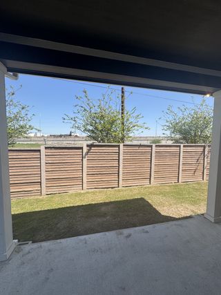Model Home A serene patio with partial shade overlooking a fenced yard and clear blue sky, perfect for outdoor relaxation.