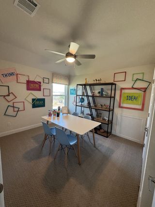 A creative workspace featuring a sleek white table, pastel chairs, and vibrant wall decor.