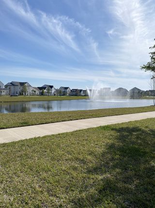 A picturesque community pond with a fountain, lush greenery, and a walking path for peaceful strolls in Seven Pines.