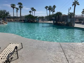A serene pool with palm trees and lounge chairs at Magnolia at Desert Passage by KB Home in Maricopa, AZ.