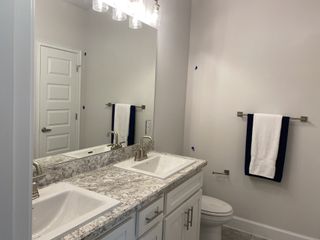 A modern bathroom featuring dual sinks with a granite countertop, sleek fixtures, and elegant lighting.