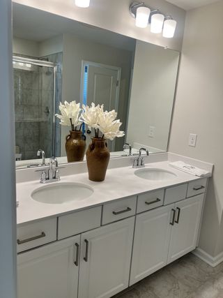 A luxurious bathroom with a double vanity, white cabinetry, and elegant lighting, bringing a spa-like ambiance to the space.