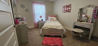 A cozy bedroom with a tufted bed, pink accents, and a chic vanity, perfect for a charming and inviting space.