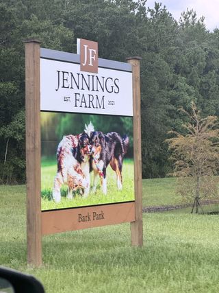 A welcoming bark park sign at Jennings Farm by LGI Homes in Middleburg, FL, surrounded by lush trees and greenery.