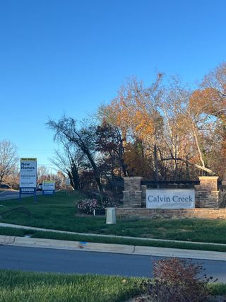A welcoming entrance in Calvin Creek by D.R. Horton, featuring a stone sign and lush landscaping in Troutman, NC.