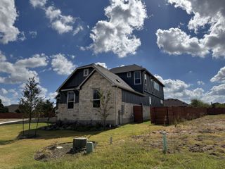 A charming stone and dark-paneled home with a spacious yard in Broken Oak by Chesmar Homes (Georgetown, TX).