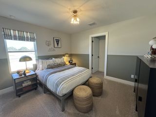 A cozy bedroom featuring a plush bed, modern lighting, and stylish decor with neutral tones and textured accents.