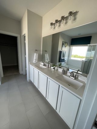 A sleek bathroom features a dual sink vanity, elegant fixtures, and a soft, neutral color palette with ample natural light.