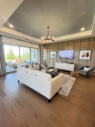 Elegant living room with wood flooring, a cozy seating area, chandelier, and a scenic view from large sliding doors.
