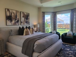 A cozy bedroom with abstract art, plush bedding, and large windows showcasing a serene backyard view.