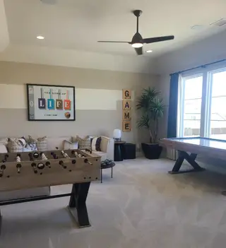 A stylish game room with foosball table, modern decor, and large windows. Cozy seating enhances the inviting atmosphere.