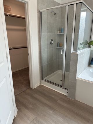 A modern bathroom featuring a sleek glass shower, tile accents, and an adjacent walk-in closet for convenience.