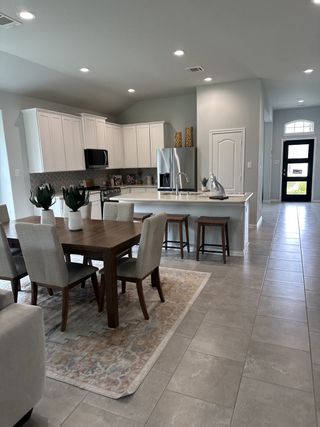 An inviting open-concept kitchen with white cabinetry, stainless appliances, and a cozy dining area with modern decor.