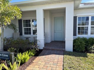 A charming white home with shutters and lush landscaping in Spirit of Sebastian by Ryan Homes (Sebastian, FL).