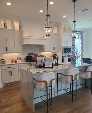 Model Home A modern kitchen with elegant white cabinetry, a sleek island, and stylish pendant lighting.