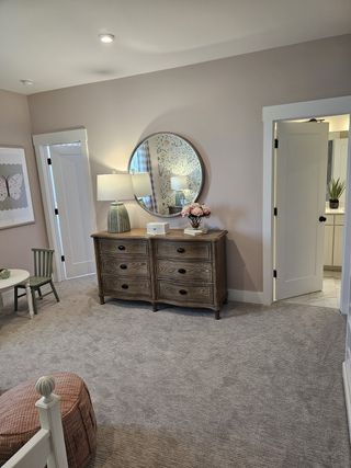 A cozy bedroom with soft carpeting, a rustic dresser, and elegant décor, offering a warm and inviting retreat.