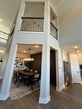 A chic dining area with a high ceiling, elegant lighting, modern decor, and a cozy rug accents the space beautifully.