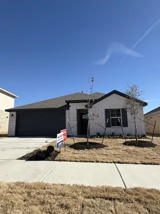 A sleek brick home with dark shutters and a neat yard in Bar W Ranch by D.R. Horton (Leander, TX).