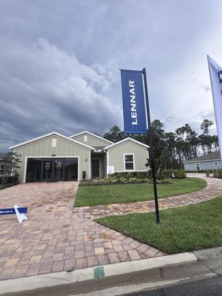 A modern green home with a paved driveway and lush lawn in Trailmark by Lennar (St. Augustine, FL).