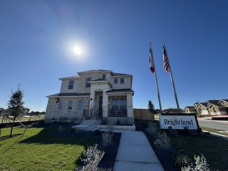 A beautiful brick home with modern design in Opal Ranch by Brightland Homes, featuring landscaped lawns in Kyle, TX.
