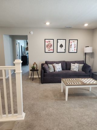 A cozy living room with plush carpeting, contemporary art, and a comfortable gray sofa.