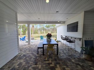 A stylish outdoor patio with a brick floor, covered seating area, and a scenic lake view in Brookside at Shearwater by David Weekley Homes (St. Augustine, FL), perfect for entertaining.