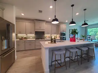 Model Home A modern kitchen featuring pendant lights, sleek cabinetry, a large island, and stylish seating for casual dining.