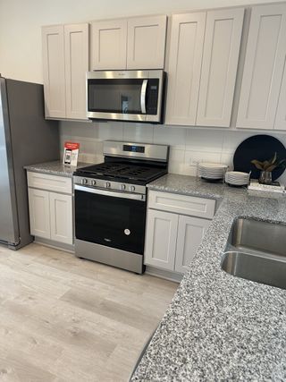 A modern kitchen with sleek gray cabinets, stainless steel appliances, and granite countertops.