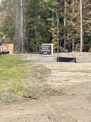 A serene entrance to Ashley Walk Townes by Beazer Homes, framed by lush trees in Charleston, SC.