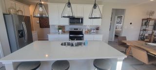 A sleek and contemporary kitchen with stainless steel appliances, subway tile backsplash, and a spacious island with bar seating.