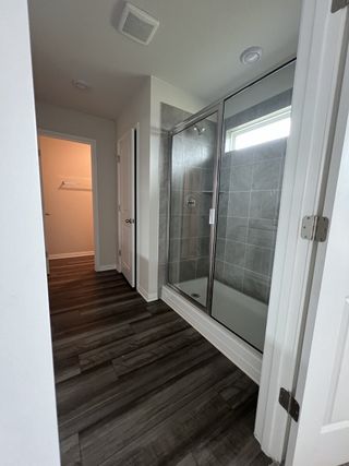 A contemporary bathroom with a glass shower, gray tiled walls, and rich wood flooring for a sleek finish.
