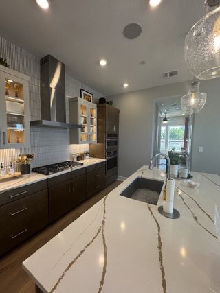 Model Home A sleek kitchen featuring a marble island, modern cabinetry, and elegant lighting fixtures.