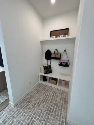 A cozy mudroom nook with brick-style flooring, wall hooks, and storage cubbies for organization and style.