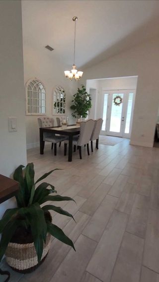 An elegant dining room with high ceilings, chic lighting, and stylish seating. Natural light enhances the airy ambiance.