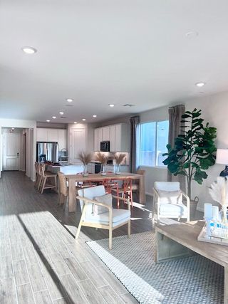 A bright, open-concept living area with wood floors, modern kitchen, and cozy seating, filled with natural light.