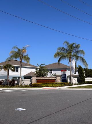 A grand entrance to Winding Meadows by Pulte Homes (Apopka, FL), featuring elegant brick columns and lush greenery.