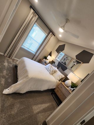 A cozy bedroom with elegant gray accents, patterned wall art, and warm lighting, complete with plush carpeting.