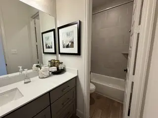 A modern bathroom with sleek countertops, elegant framed art, and a tiled shower area for a stylish finish.