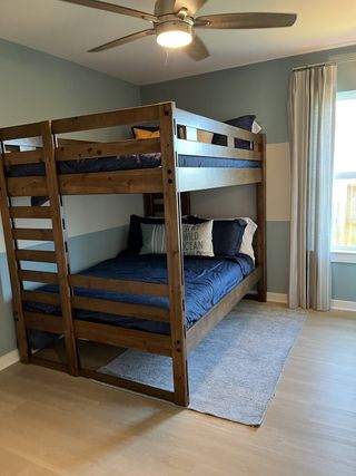 Model Home A cozy bedroom with wooden bunk beds, blue bedding, soft lighting, and soothing blue walls, creating a tranquil space.