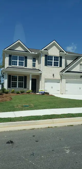A beautiful two-story home with white brick and a manicured lawn in Butner Estates by D.R. Horton (South Fulton, GA).