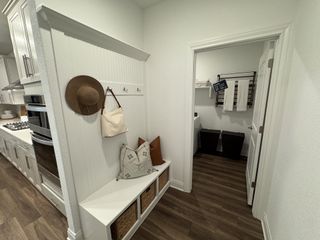 A cozy mudroom with hooks, a storage bench, and elegant wood floors next to a functional laundry space.