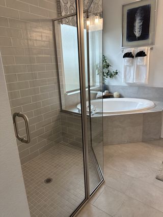 A contemporary bathroom featuring a sleek glass shower, elegant tub, and modern decor with soft lighting.