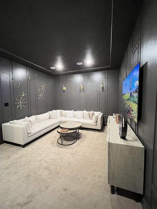A sleek media room with a cozy white sectional, elegant wall decor, and ambient recessed lighting.