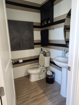 A modern bathroom with striped walls, sleek fixtures, and wood-look flooring.