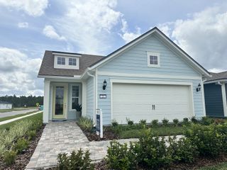 A charming light blue cottage-style home with a welcoming front porch in Summer Bay at Grand Oaks by Pulte Homes (St. Augustine, FL).
