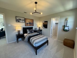 Model Home A cozy bedroom featuring music-themed decor, modern lighting, and a sleek black bed with striped bedding.