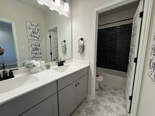 A modern bathroom with dual sinks, star-patterned tiles, and a sleek, dark-tiled shower.
