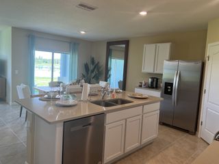 A modern kitchen with sleek white cabinetry, stainless steel appliances, and a spacious island overlooking a bright dining area.